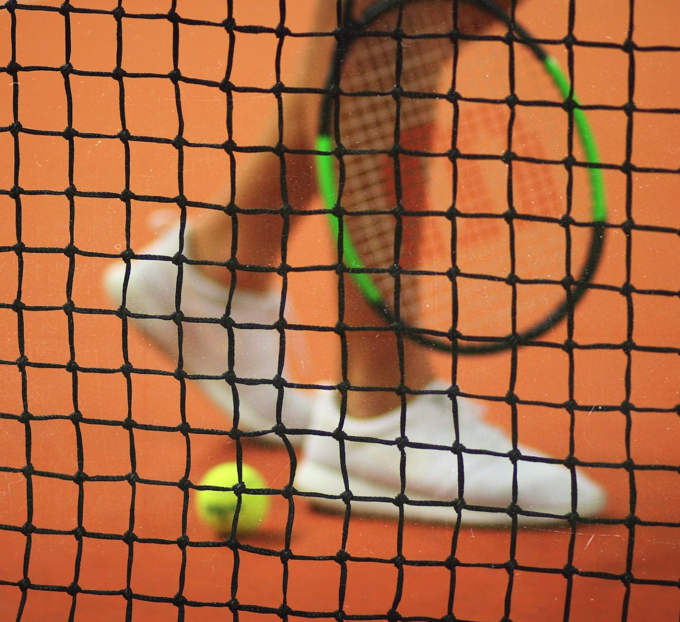 person walking behind net with racquet and ball