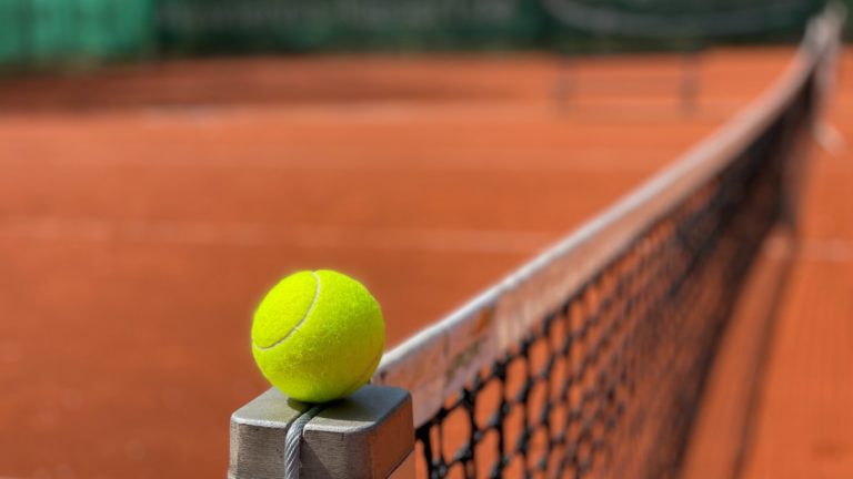 tennis ball on edge of net